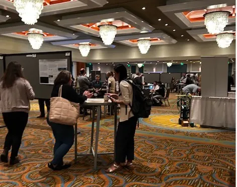 Two people stand at a table chatting