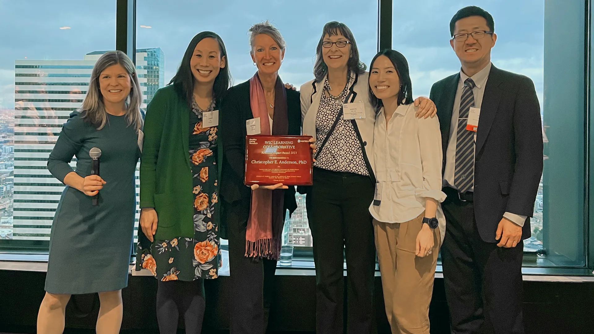 A group of scholars receive a certificate recognizing the work of a colleague