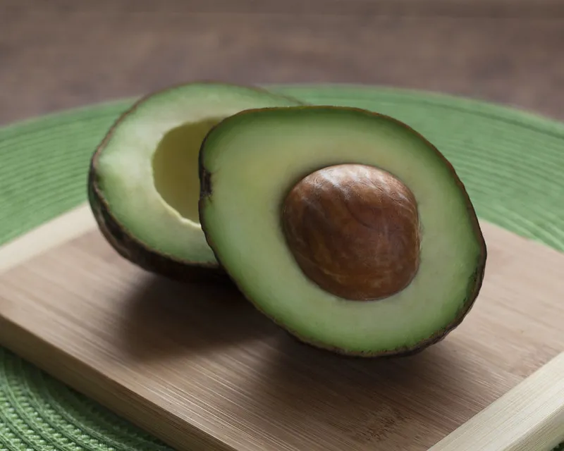 cut avocado displaying brown pit and green flesh