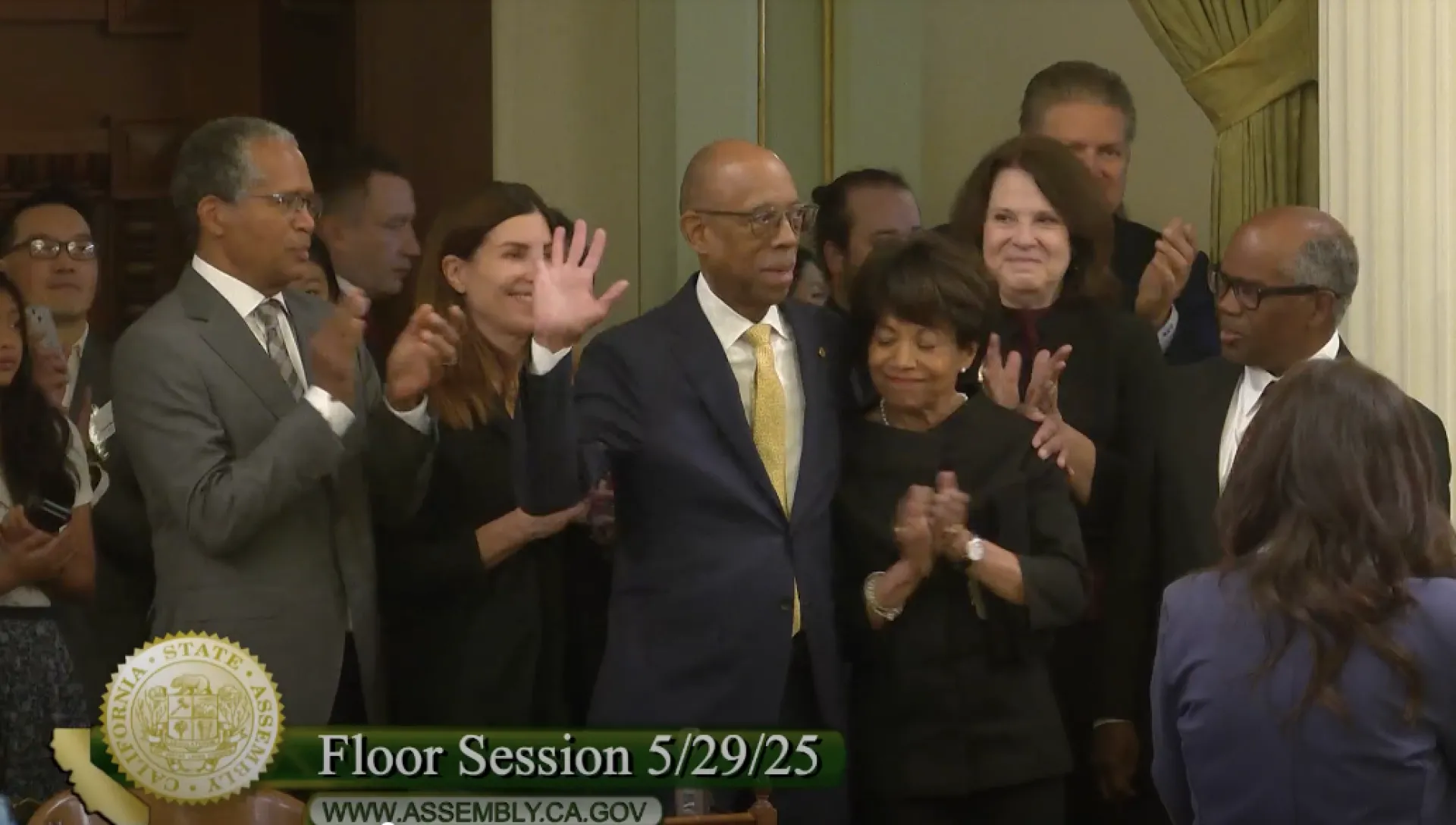 Surrounded by his family, President Drake waves at assemblymembers who applaud his career