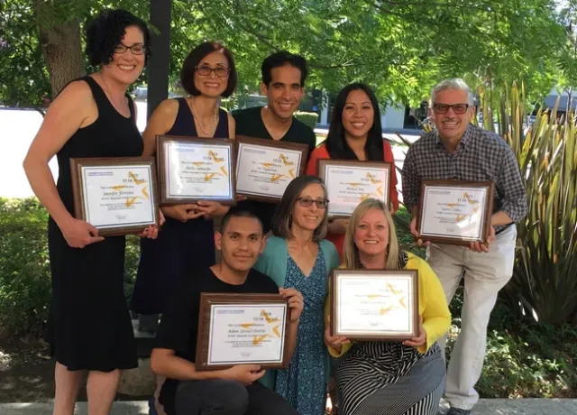 Santos, on right, poses with 6 team members holding their certificates outdoors