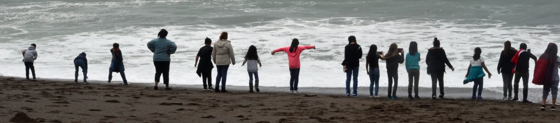 17 adults and children stand at the water's edge