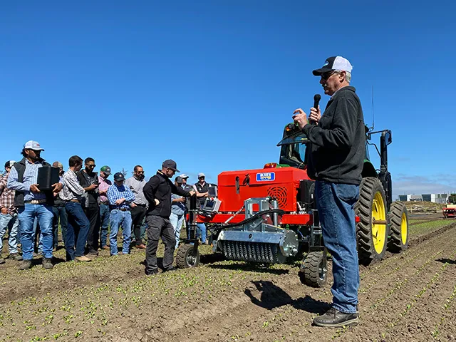 Steve Fennimore holds a microphone as he speaks at a field day