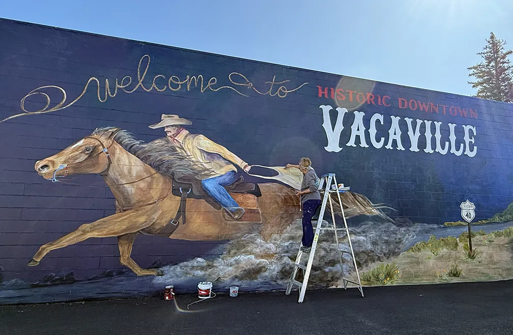 Joi McNeil at work on her mural in historic downtown Vacaville. (Photo by Kathy Keatley Garvey)