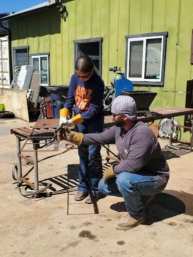 Adult volunteer is helping 4-H youth learn to weld