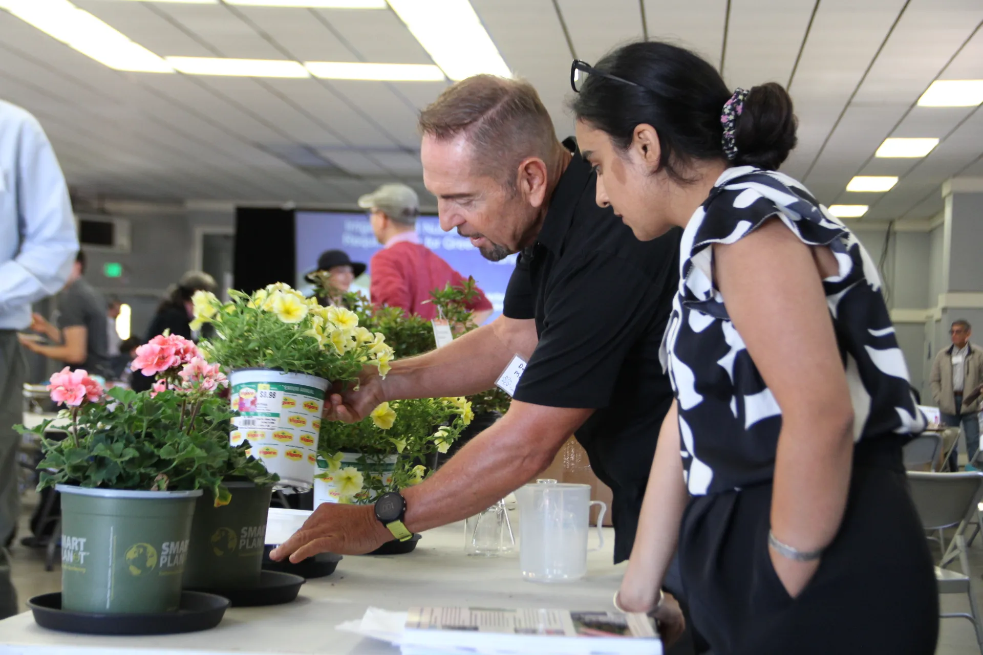 Two people look at potted plants.