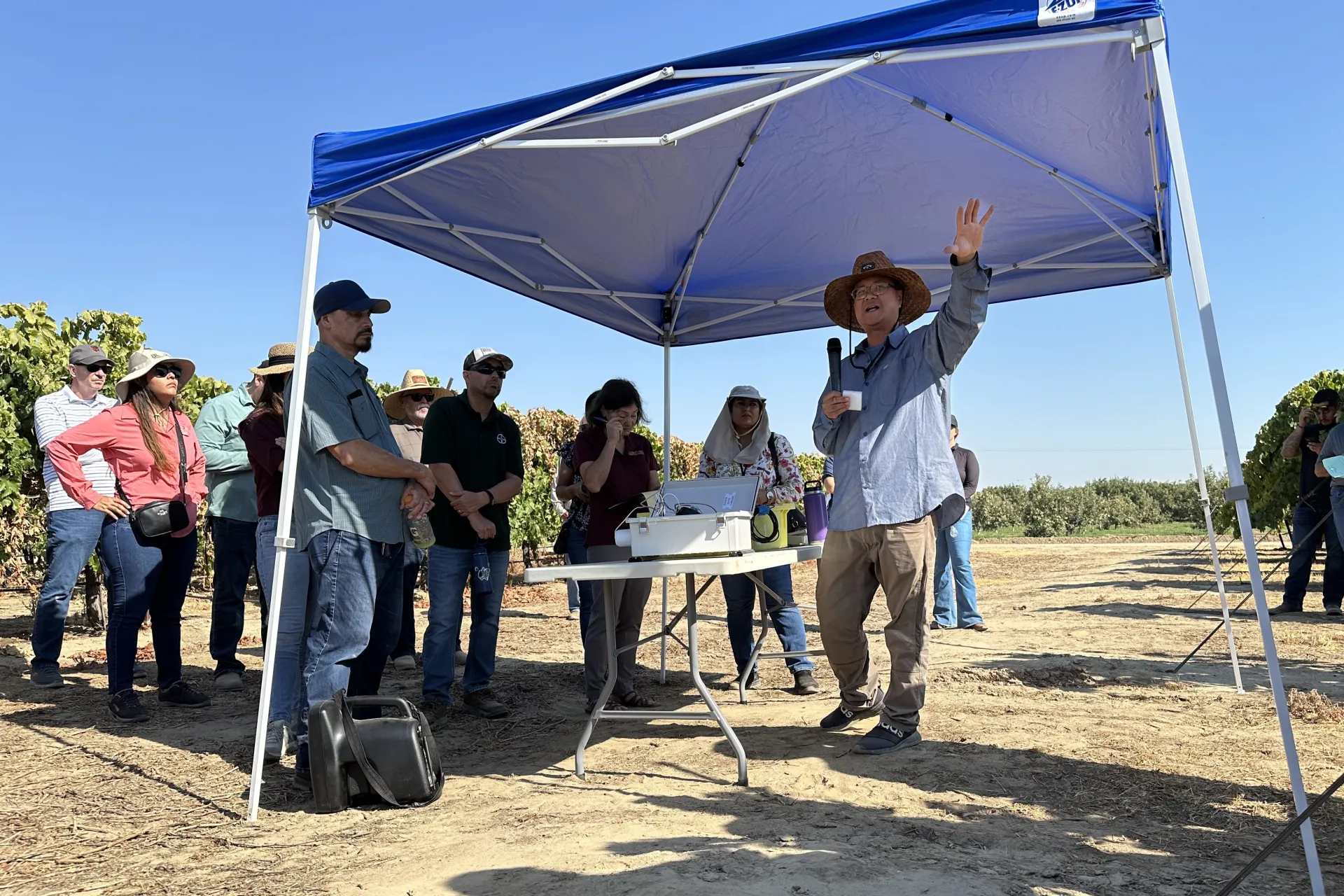 George Zhuang gestures as he stands by a table full of instruments in a vineyard at Kearney REC