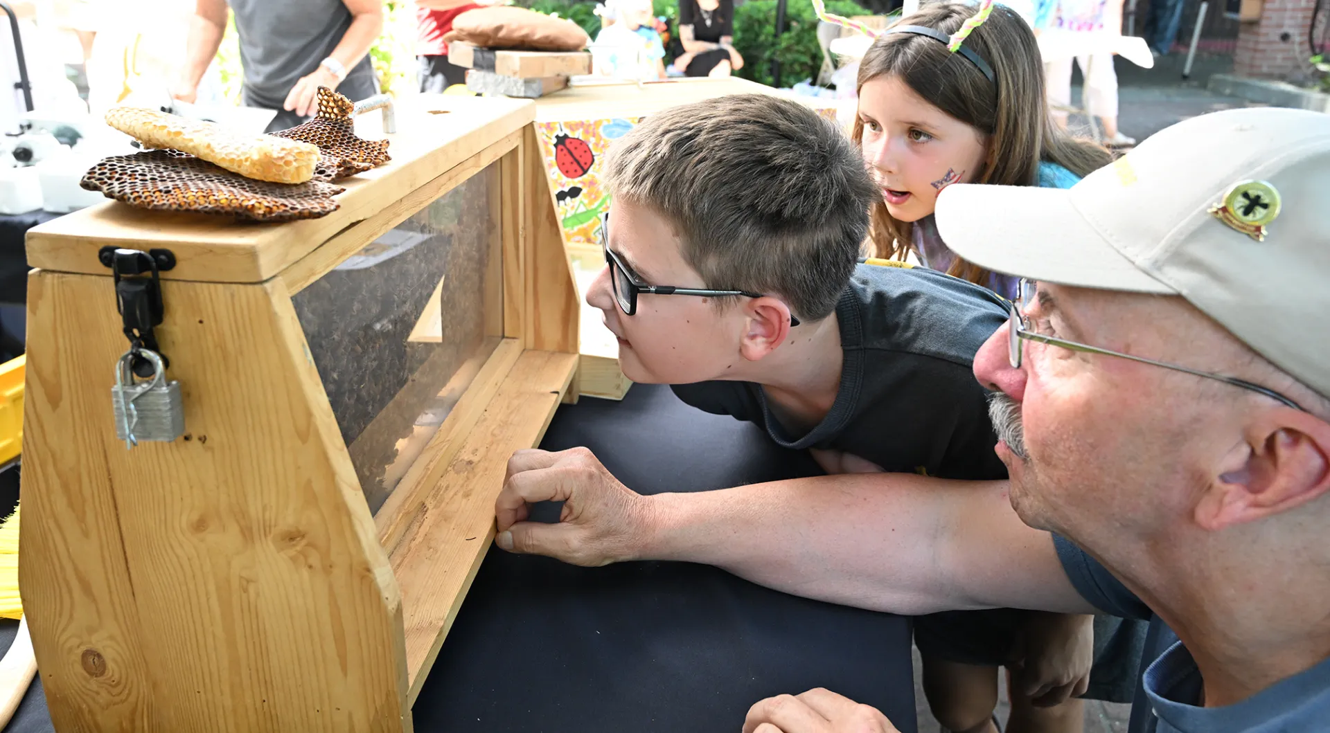 CAMBP beekeeper Rick Moehrke, a retired Vacaville teacher, talks to Max Hensley, 8, and his sister, Brynn, 6, as they look for the queen. (Photo by Kathy Keatley Garvey)