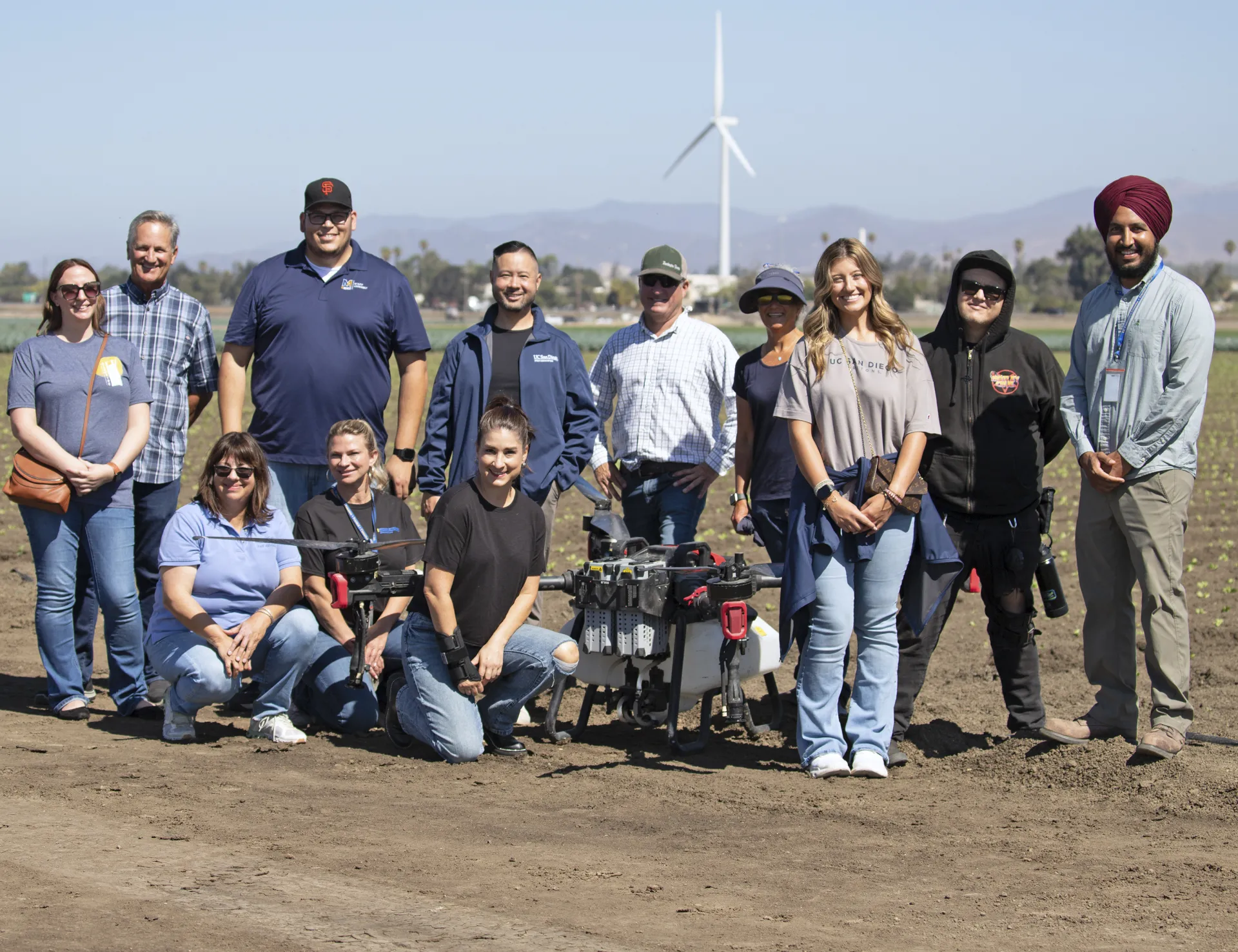 Group poses around a drone