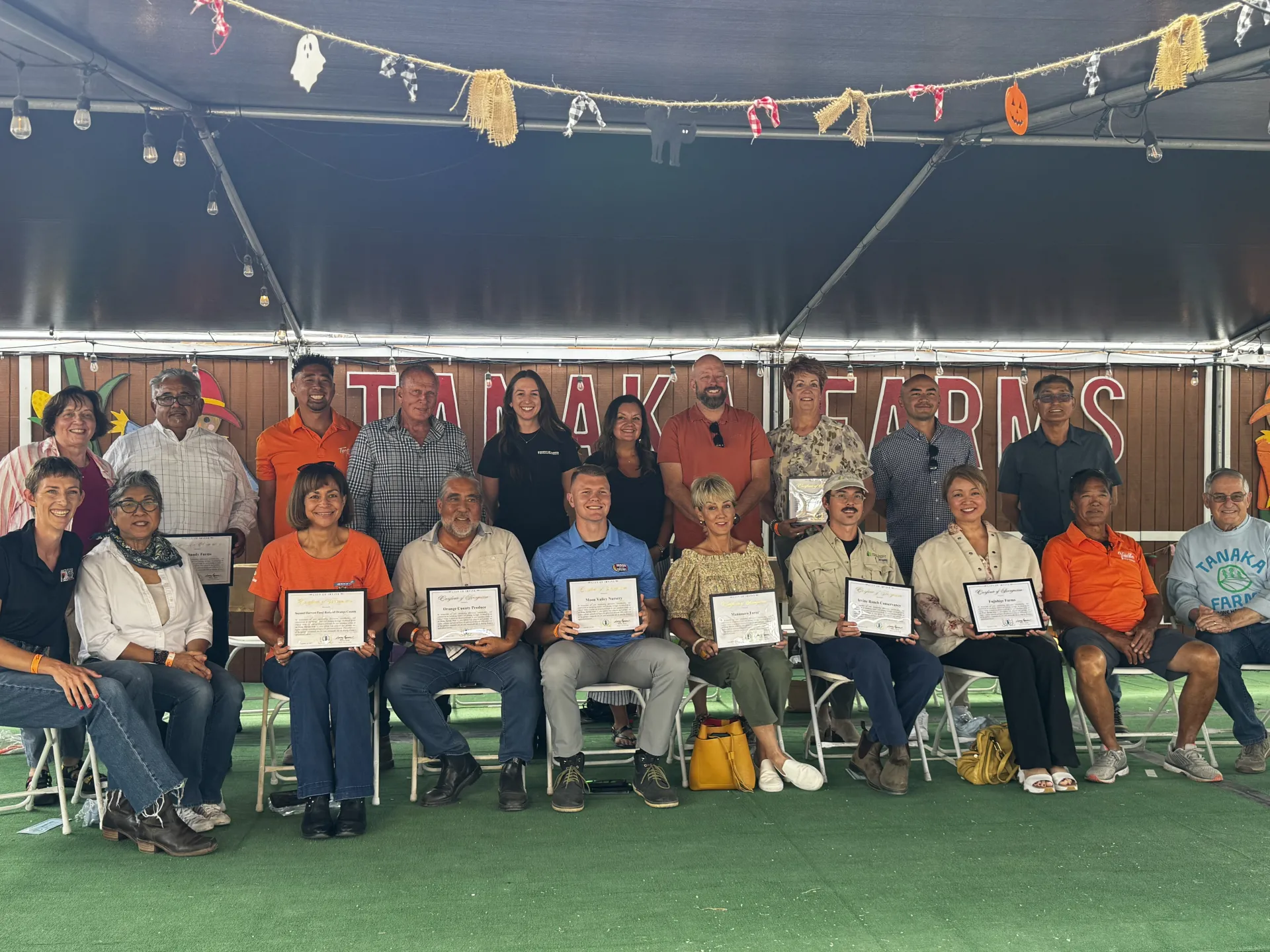 People holding award certificates sit in a row