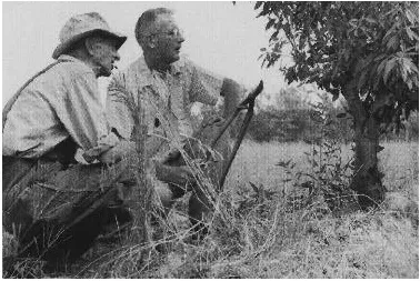 Two men sitting near tree black and white photo