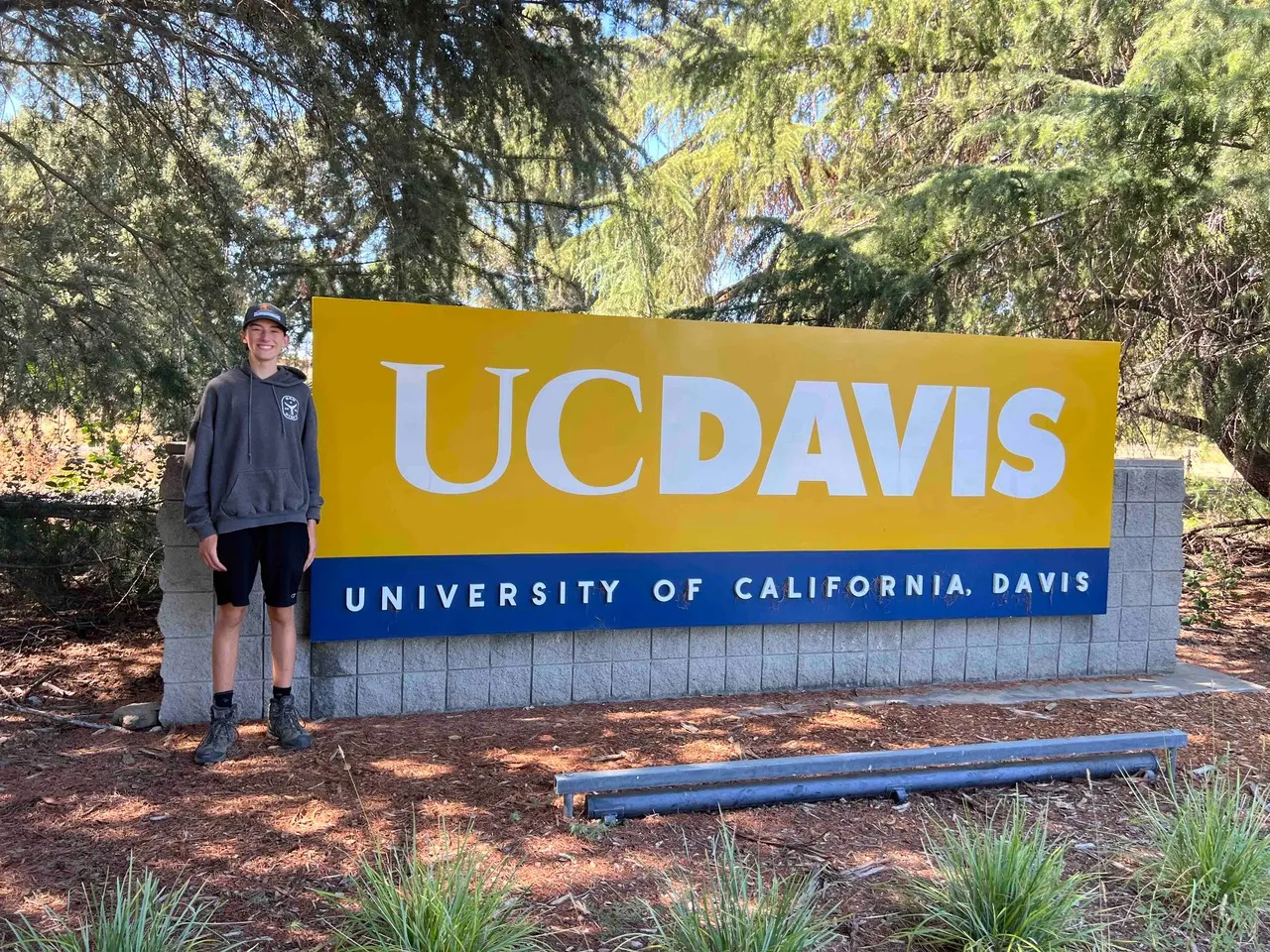 Young entomologist Cole Kramer in front of a UC Davis sign. 