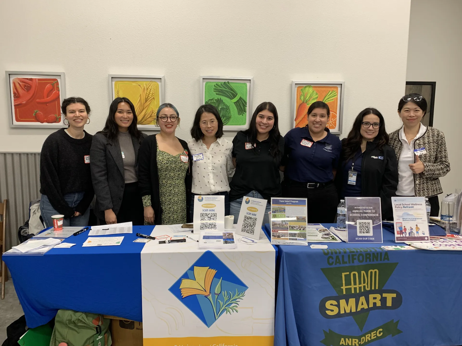 Eight women stand behind the Master Gardener and Farm Smart tables