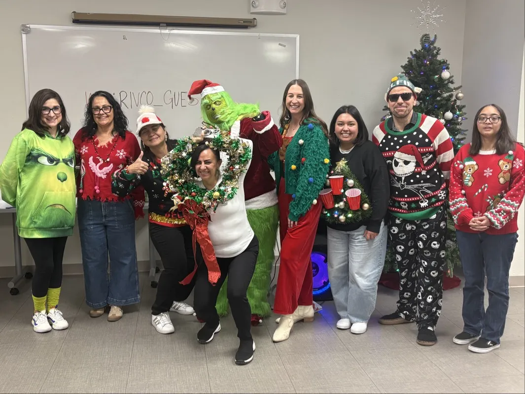A group photo of people in holiday sweaters and costumes