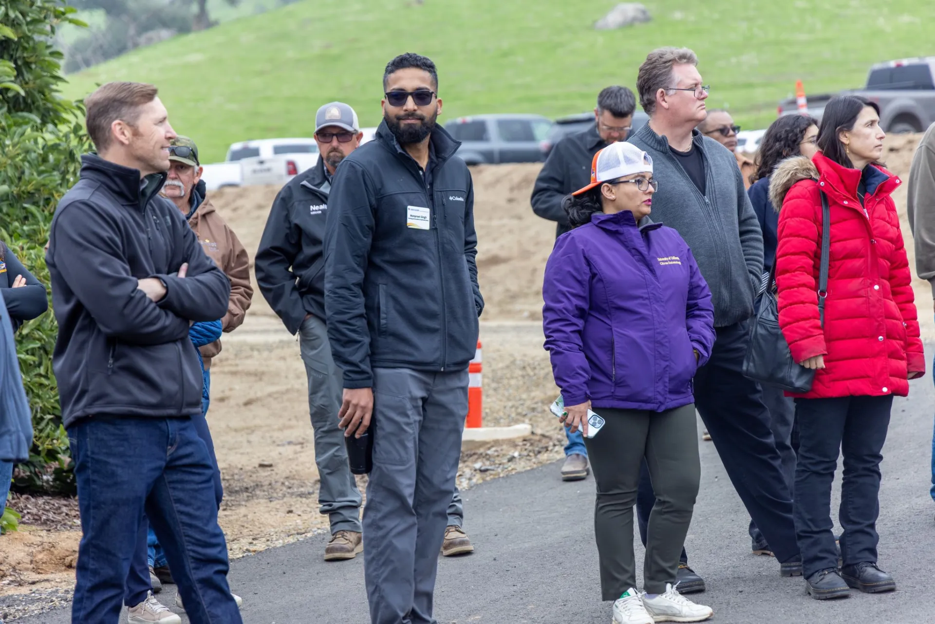 People wearing jackets standing outside with grassy field behind them