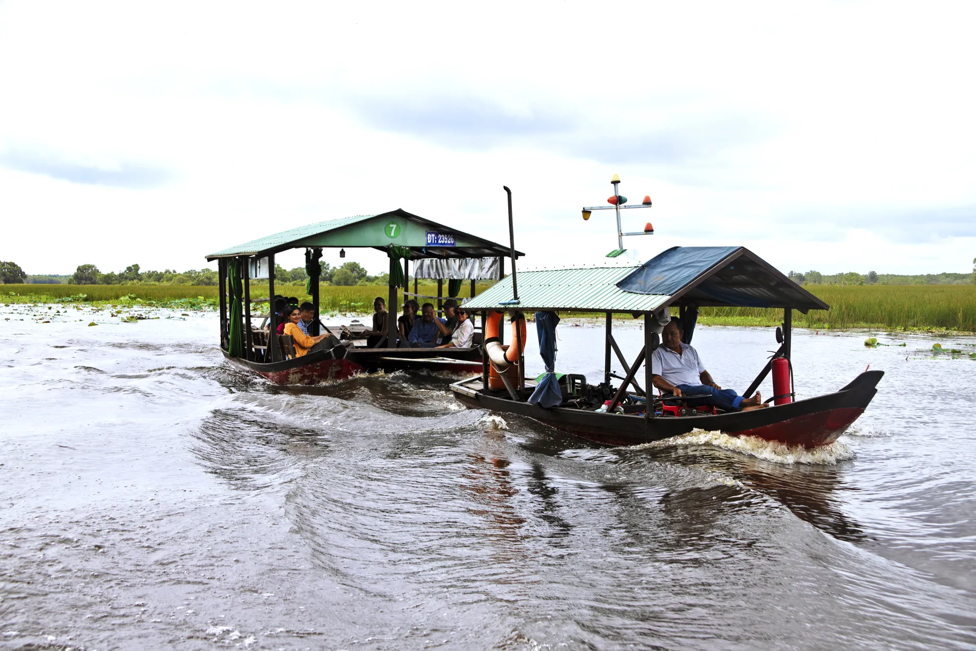 A boat with a driver pulls a trailer full of tourists through the water