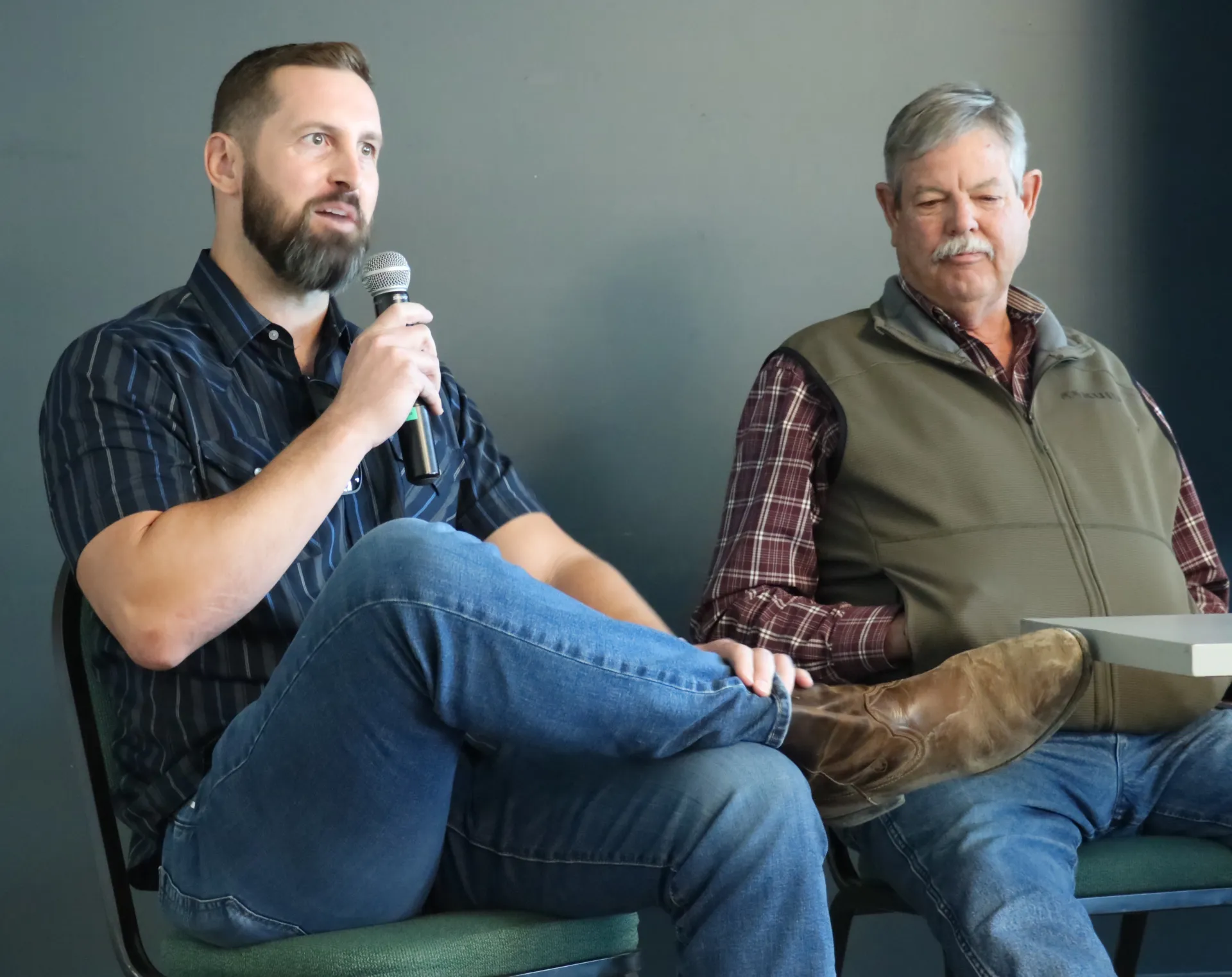 A panelist sitting and speaking into a microphone while another panelist listens