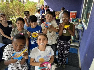 A group of 4th and 5th grade students smiling at the camera while showing off the healthy snacks they made during EFNEP class.