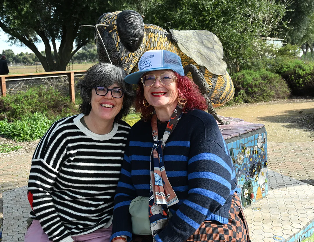 Two women in front of a bee statue