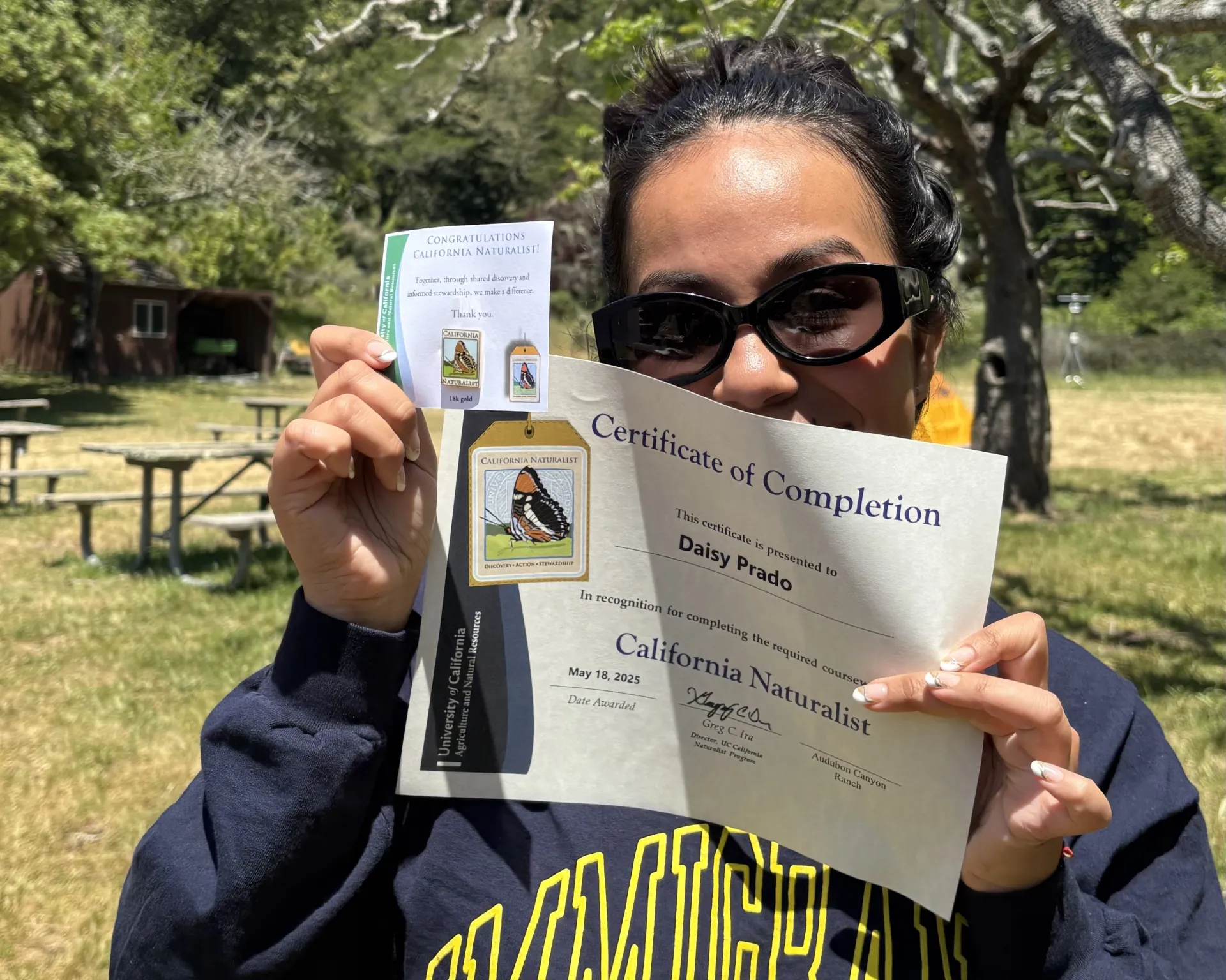 Daisy holds up her certificate of completion for a UC California Naturalist course delivered by All Hands Ecology
