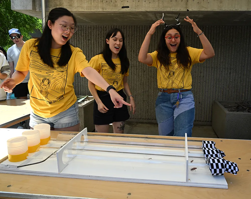Three graduate students at UC Davis cheering during a cockroach race.