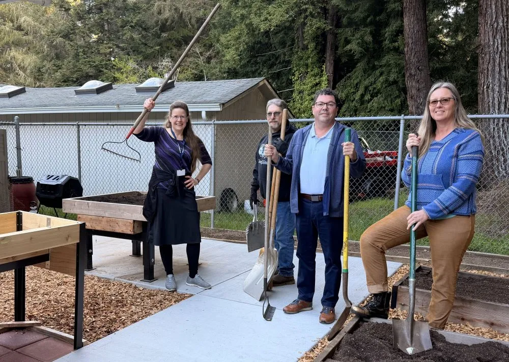 Four people holding garden tools in the Glen Paul School Garden