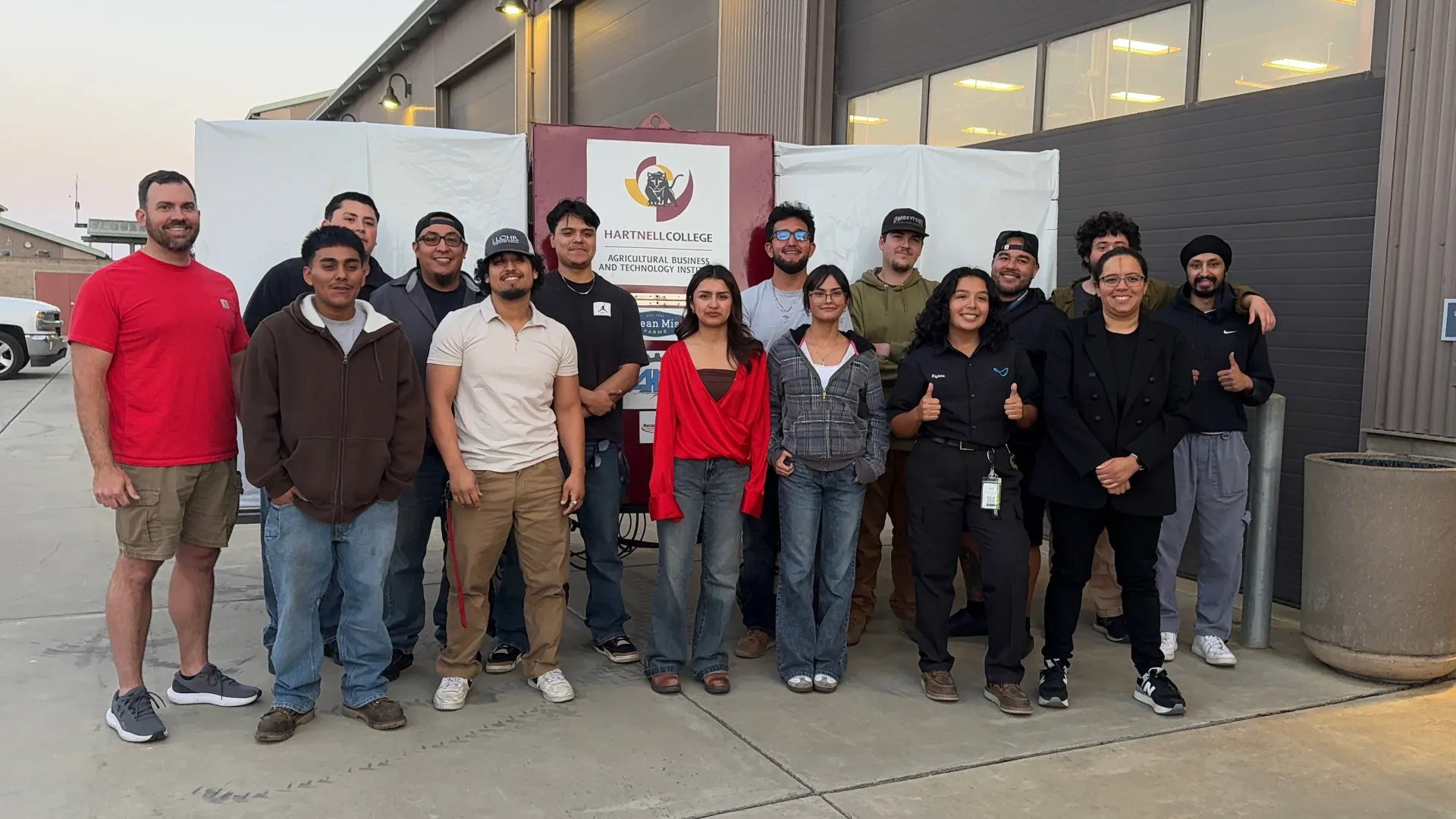 A farm robotics team stands in front of a backdrop that reads Hartnell College