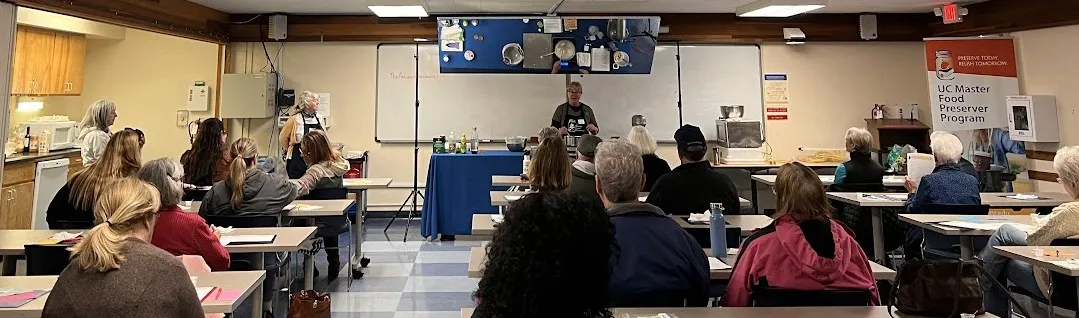 a volunteer demonstrating with cooking equipment in a classroom setting