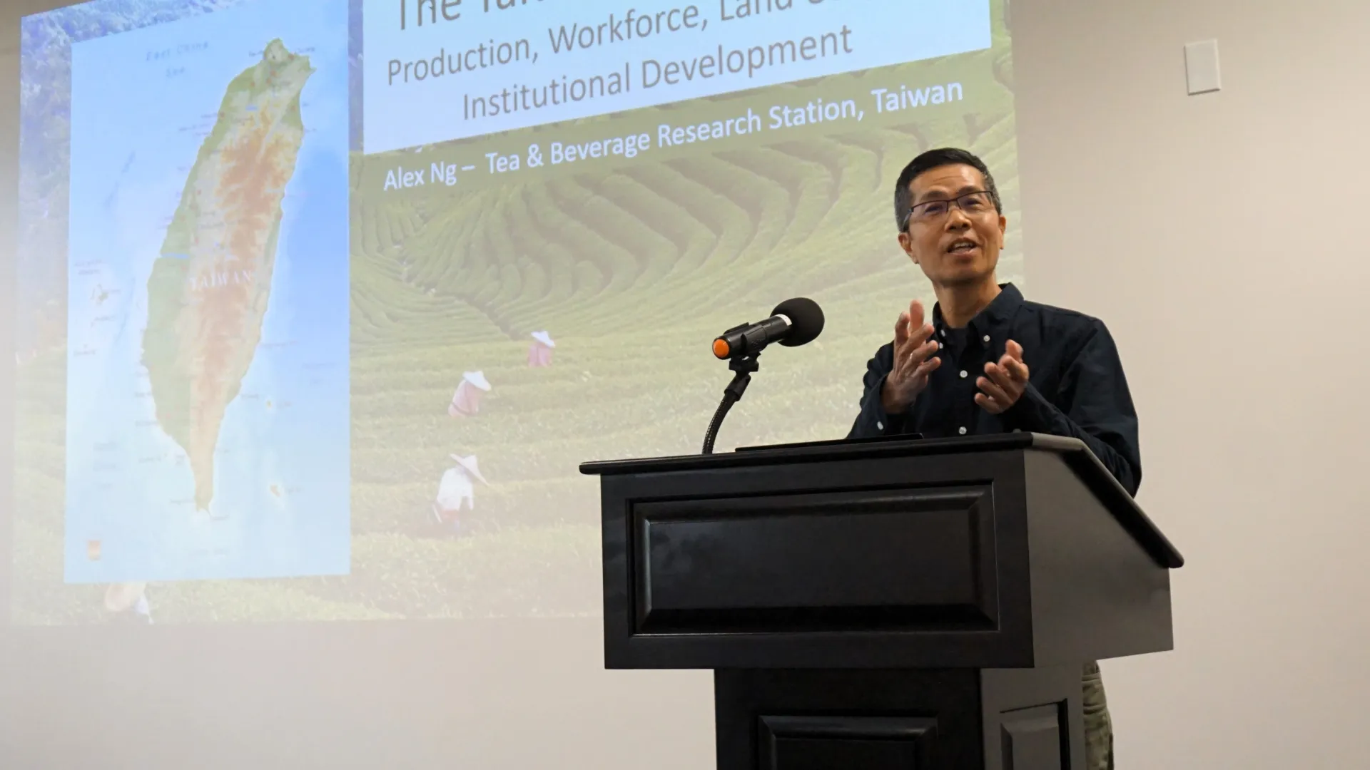 Alex Ng speaks at a podium about the development of Taiwan's tea industry