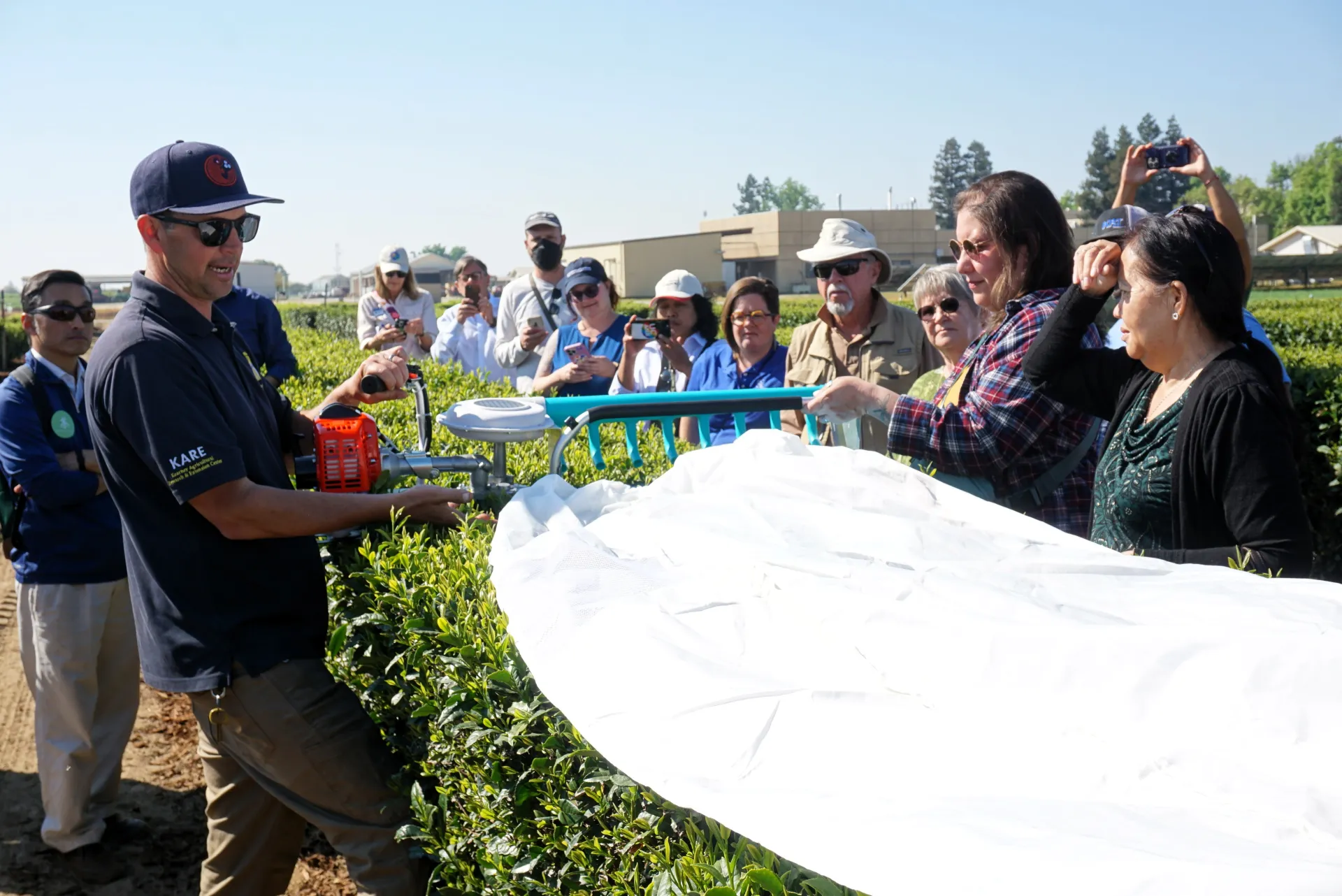 Ryan Puckett of Kearney REC shows a tea harvester, which looks an electric hedge trimmer, to the crowd at Tea Day