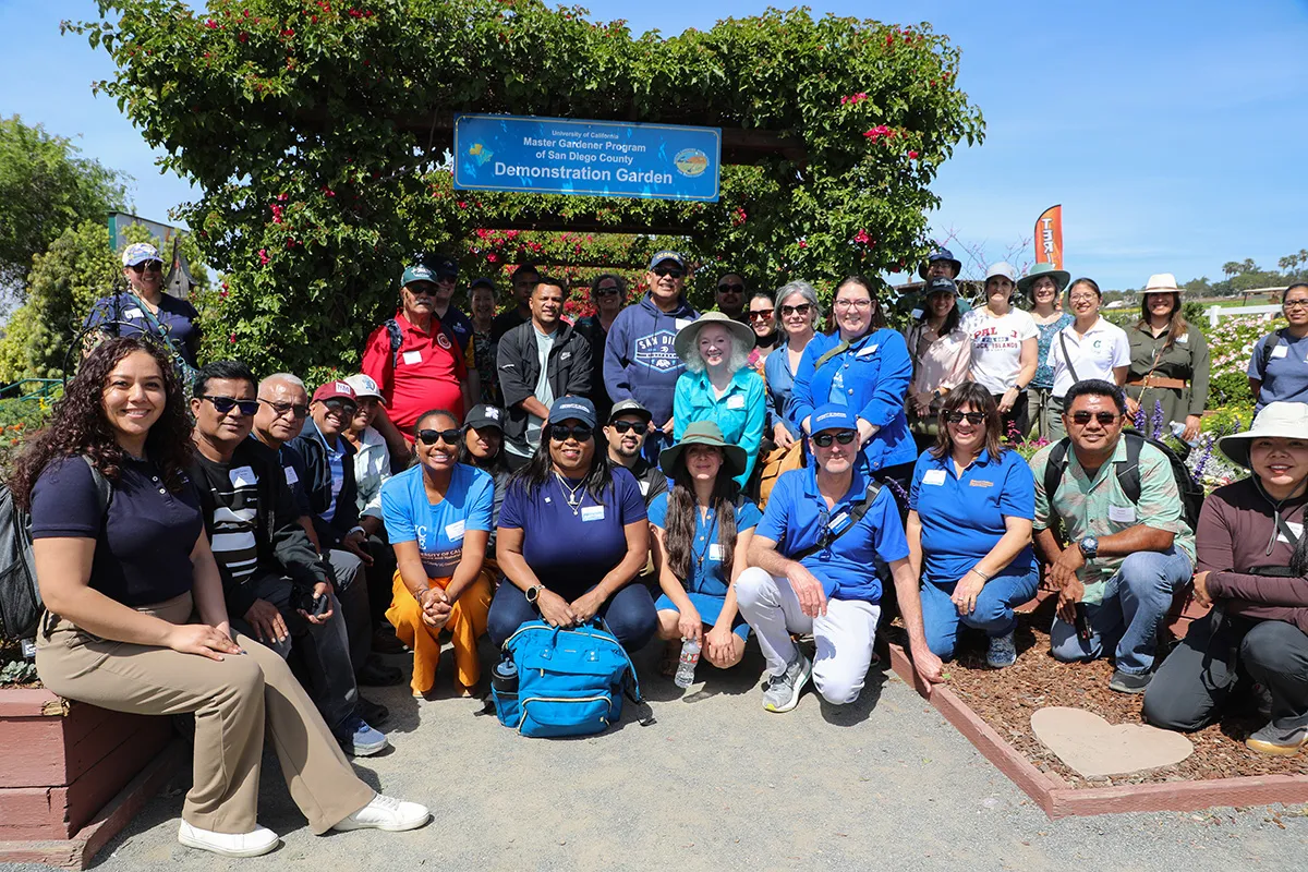 Group photo of 33 people standing and sitting in front of sign: University of California Master Gardener Program of San Diego County Demonstration Garden