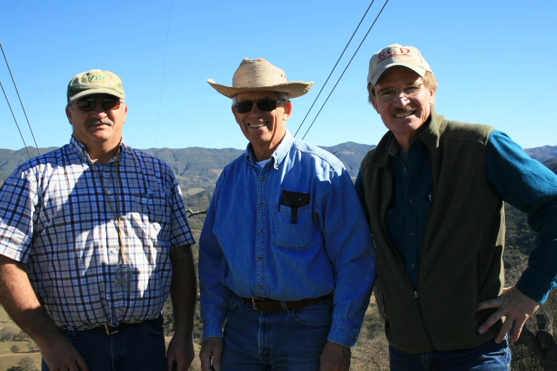 Three men stand together at a ranch