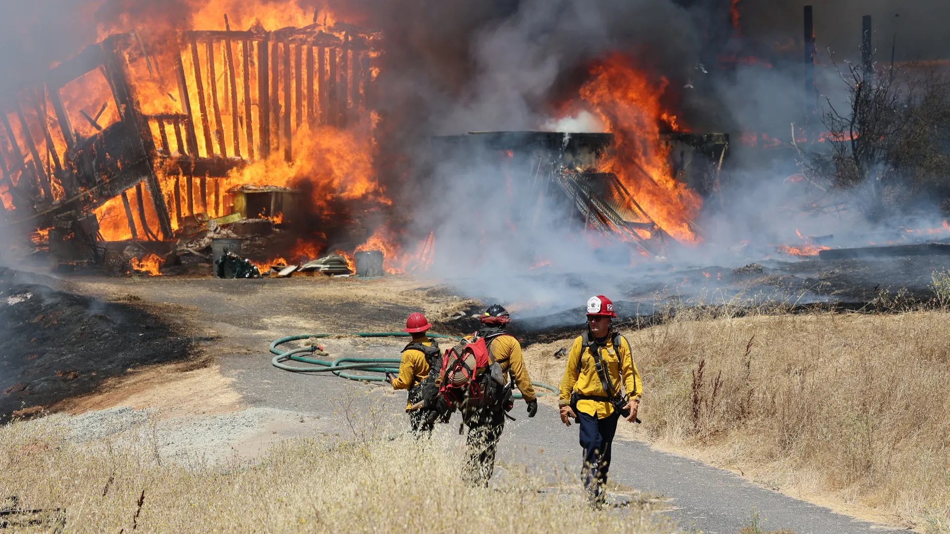 Firefighters standing in front of structure on fire