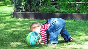 child playing with a ball on a lawn