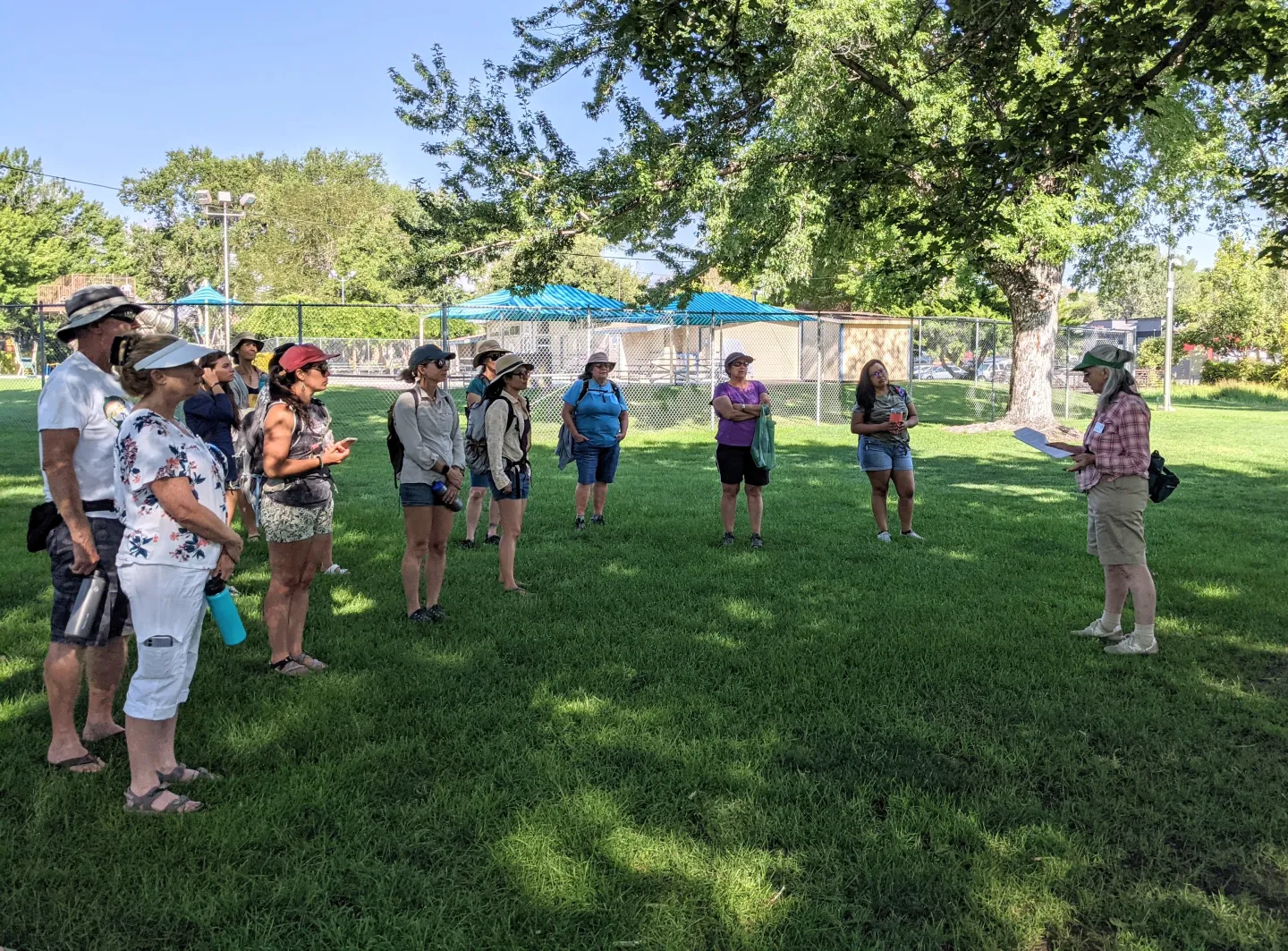 A crowd of people listening to a speaker in a park