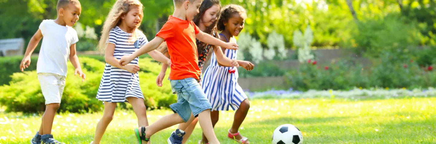 Children playing soccer in grass field