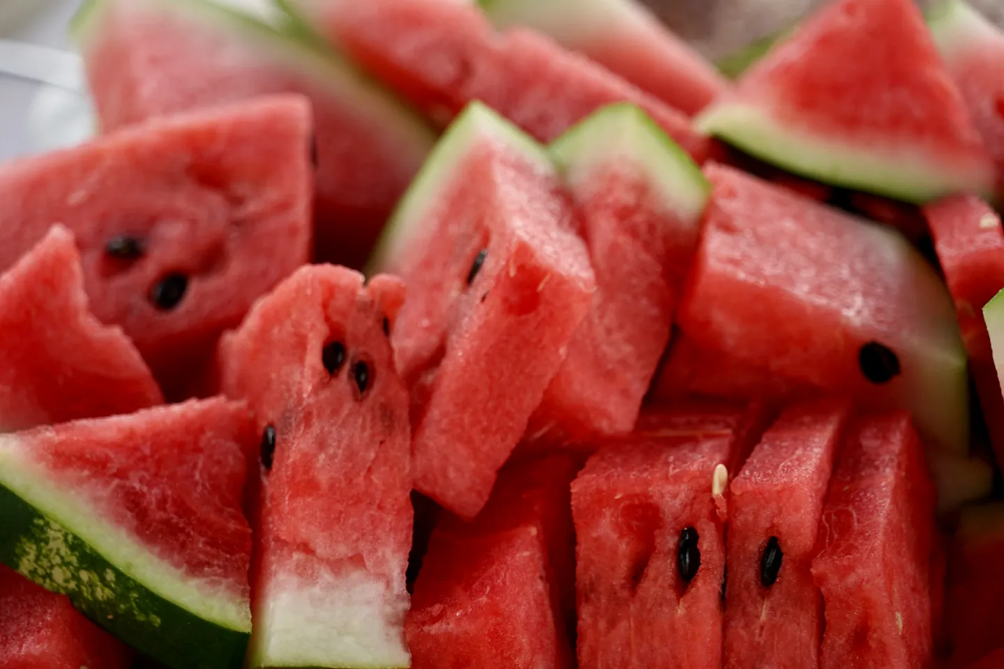 red watermelon with seeds cut into triangles with rinds on