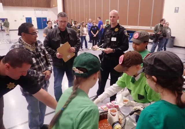 El equipo Sherwood Forest 4-H'ers se prepara para servir su chili a los jueces. De izquierda a derecha, el agente de la policía de Vacaville, Jeremy Johnson; el supervisor del condado de Solano, John Vásquez Jr., y los agentes de la policía de Vacaville, Shawn Windham y Steve Moore. Windham también es presidente de la Junta de Fideicomisarios del Distrito Escolar Unificado de Vacaville. (Fotografía: Kathy Keatley Garvey).