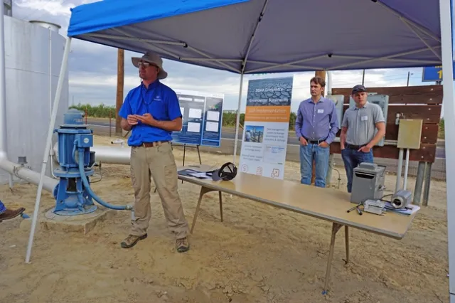 Representatives of PowWow Energy meet with Open Farm participants near a well at the UC Kearney Agricultural Research and Extension Center.