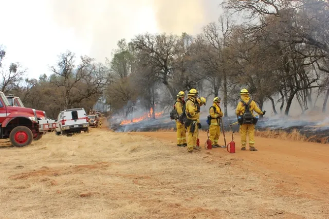 Fire truck follow behind the blaze, putting out the fire after the under brush has been cleared.