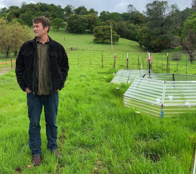 SFREC director Jeremy James stands next to a small chamber designed to simulate effects of warming air and soil temperatures on rangeland grasses. The poly carbonate hexagons slow rates of heat loss form plots, allowing scientists to artificially warm plants and soils in the chambers. (Photo: Linda Forbes)