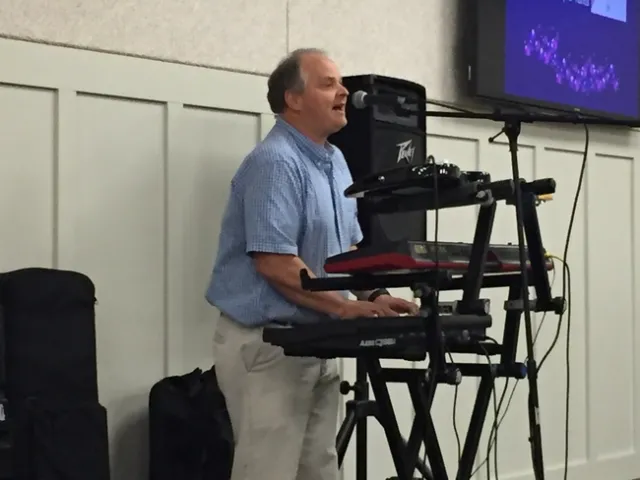 Carl Winter is shown playing at a keyboard and singing.