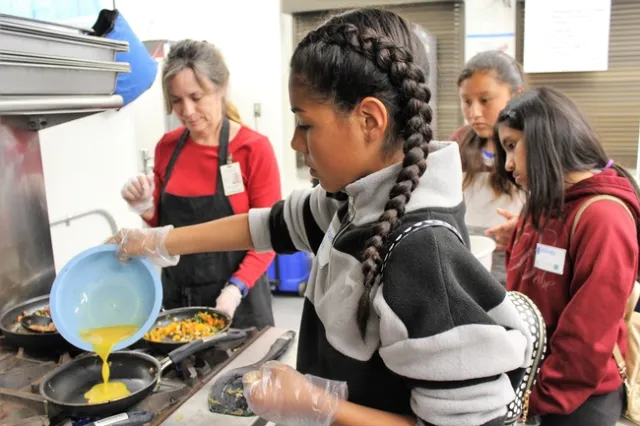Youth pouring eggs into a hot pan