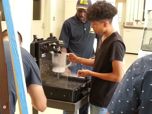 Dr.Peter Ako Larbi guides a student in measuring nozzle output volume per time, as affected by pressure.