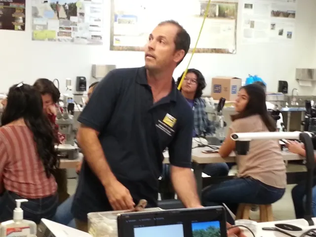 Dr.Paulo Lichtemberg adjusts a dish of microorganisms under the projection camera as his students watch.
