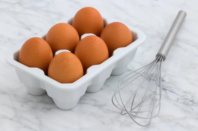 6 brown eggs and a metal whisk
