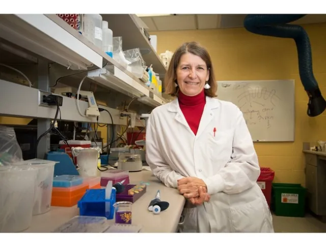 Merry Jo Velasquez in her medical research lab, wearing a white lab coat and turtle neck, surrounded by lab materials.