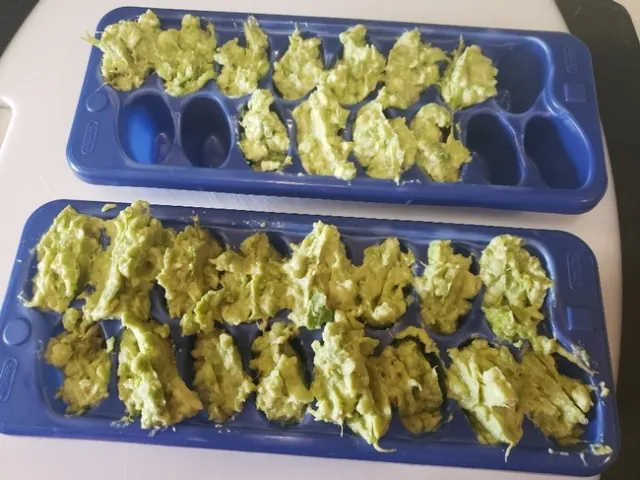 Ice cube trays loaded with mashed avocado