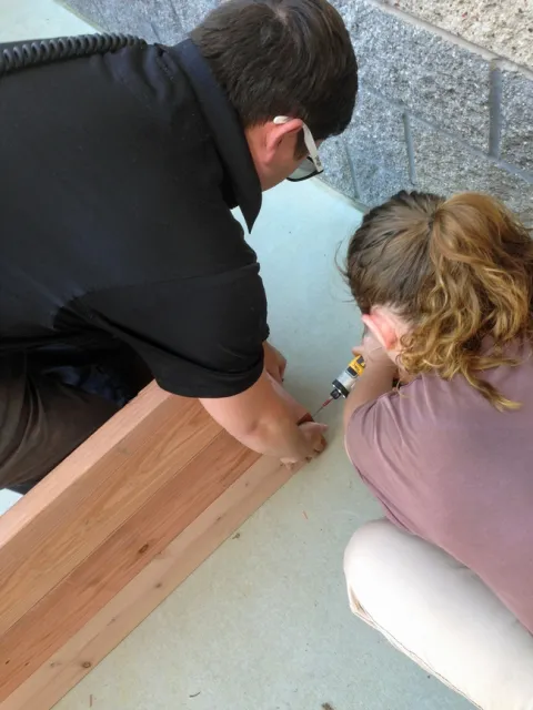 An officer helps an incarcerated youth build a garden bed.