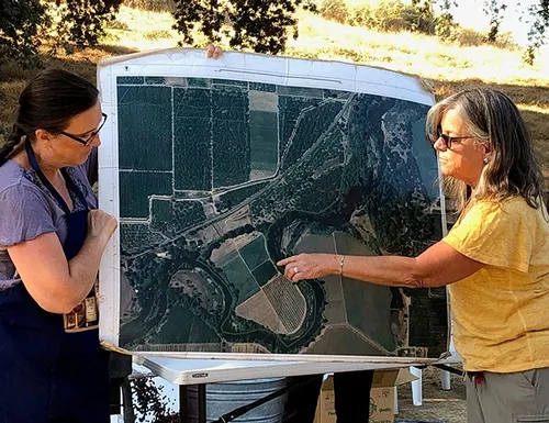 Cindy and Kathy show photo of Riverdance Farm taken from above.